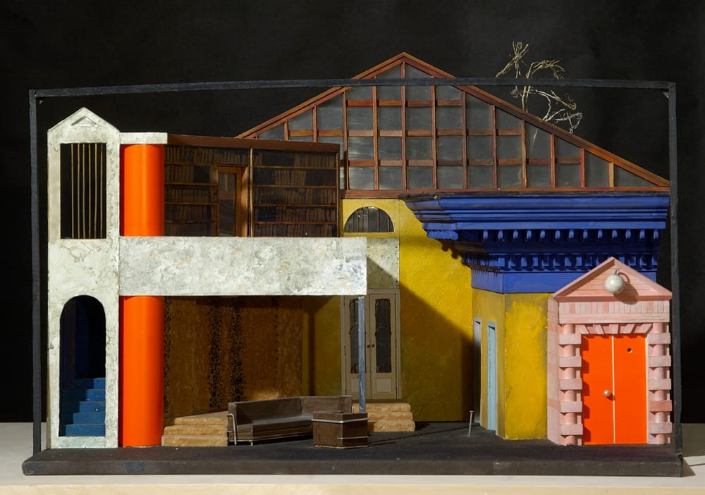 1985г. «Кто боится Вирджинии Вульф» Э.Олби. Театр «Современник», режиссер В.Фокин. 38х56х50см. Надоела обыкновенная Америка О’Нила, Уильямса, Олби и решил сделать постмодернистский эксперимент. Огромный палладианский карниз синего ультрамарина косо стоял сбоку. Хромированная колонка двутаврового сечения поддерживала второй этаж обитый шкурками кошек с меховой фабрики (искусственного леопарда не нашли, хотя ими был завален весь Запад). Дом был очень странный, хотя понравился Д.Д.Лидеру (кажется только ему).